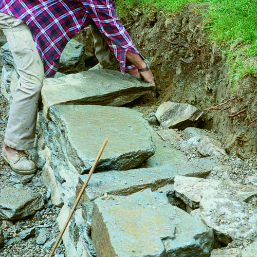 Person setting large flat stones on the retaining wall