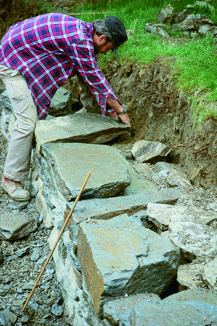 Person setting large flat stones on the retaining wall