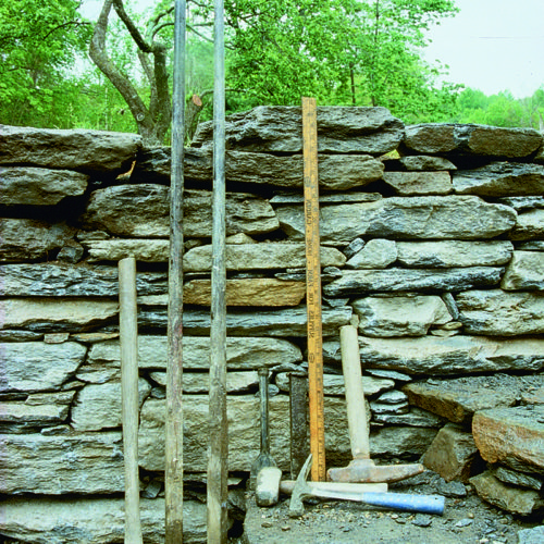 Tools leaning up against a stone retaining wall