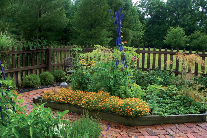 Image of Raised bed made of stone with a green wooden fence