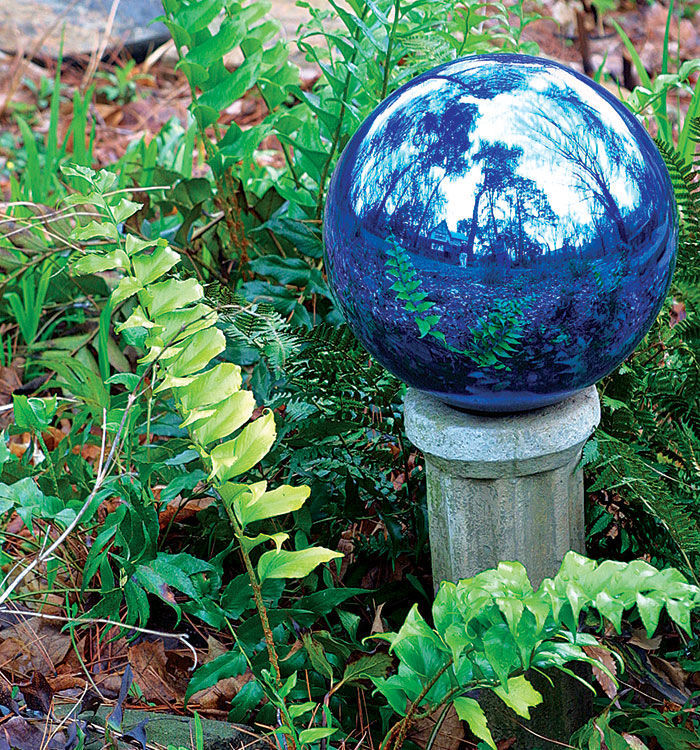 A delicate blue round garden ornament on a post in the garden