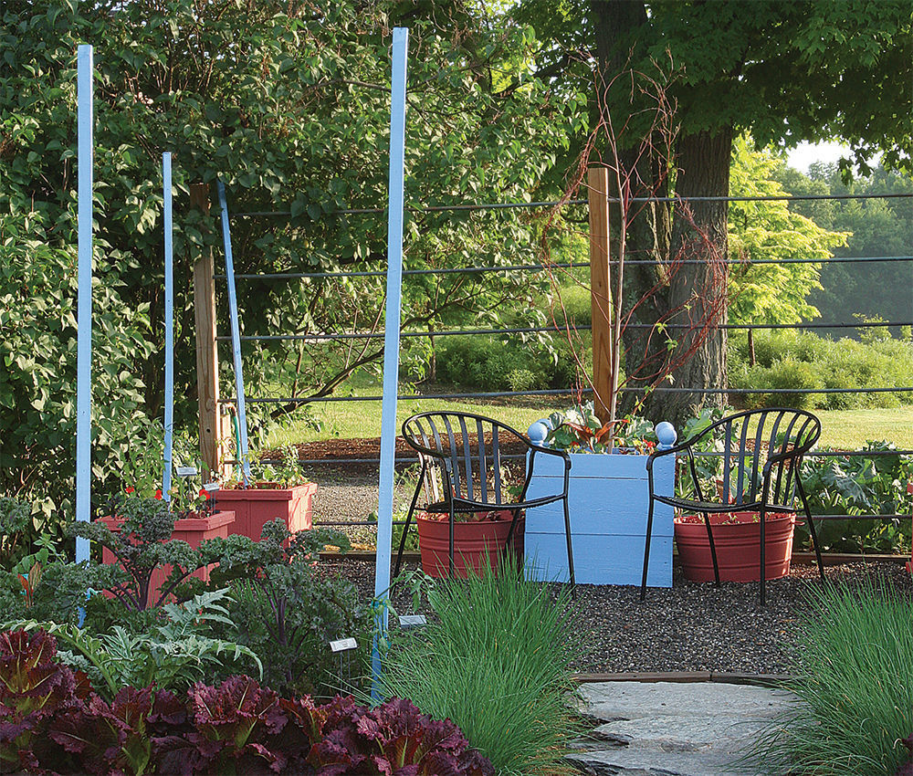 a cozy little seating area doubling as a casual work station with the planter box by the chairs painted the same color blue as the plant supports nearby.