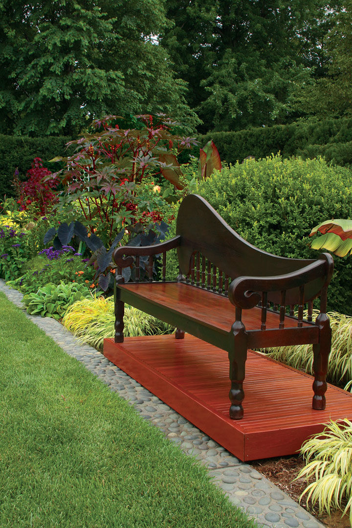 Garden bench on a platform near colorful plants