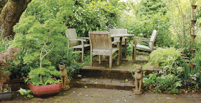 intimate seating area with table and chairs closely surrounded by flowers and foliage