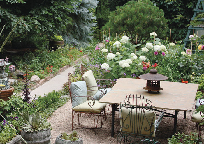 a more open seating area with table and chairs surrounded by exuberant flowers