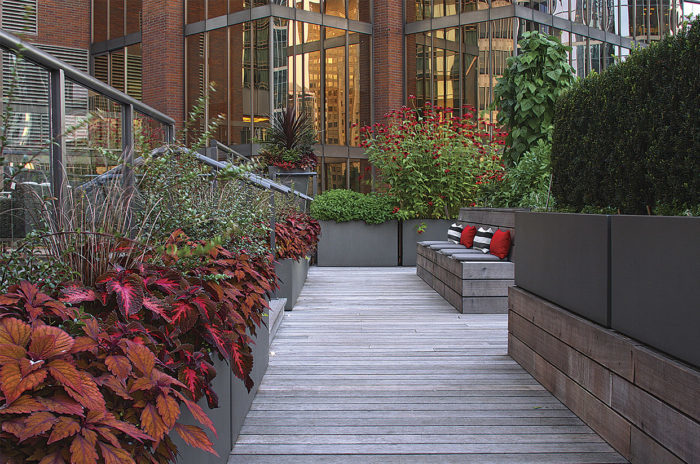 A view down a path of the garden with raised beds and built-in benches with colorful cushions