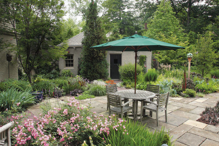 Creeping ground covers and petite grasses spill onto the flagstones to connect the patio with the surrounding garden