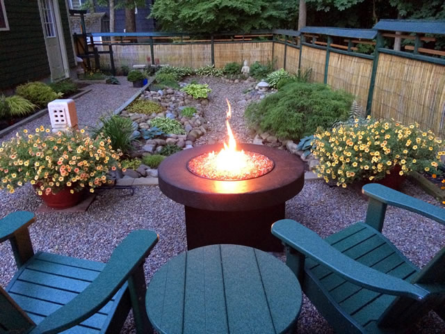 green adirondack chairs and table near a fire pit looking lengthwise down the zen garden