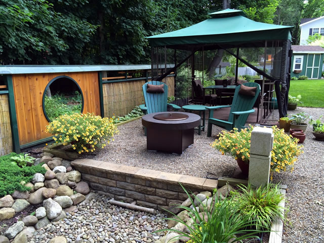 Two levels of the zen rock garden with moon window, firepit, table and chairs under a canopy