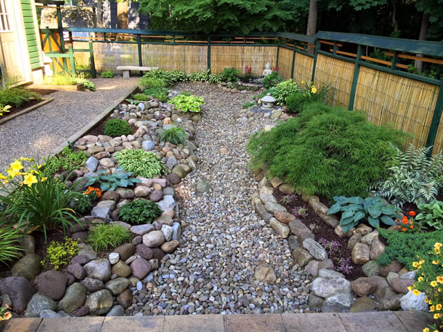 View from higher level of the zen garden showing the curving stone pathway bordered by rocks and plants