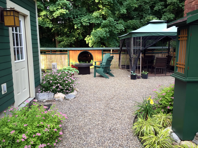 view between buildings toward chairs, fire pit, table and chairs under a canopy