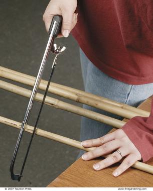 close up of person using a handsaw to cut the bamboo