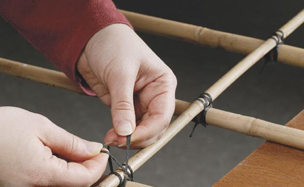 close up of hands lashing together an area of the trellis