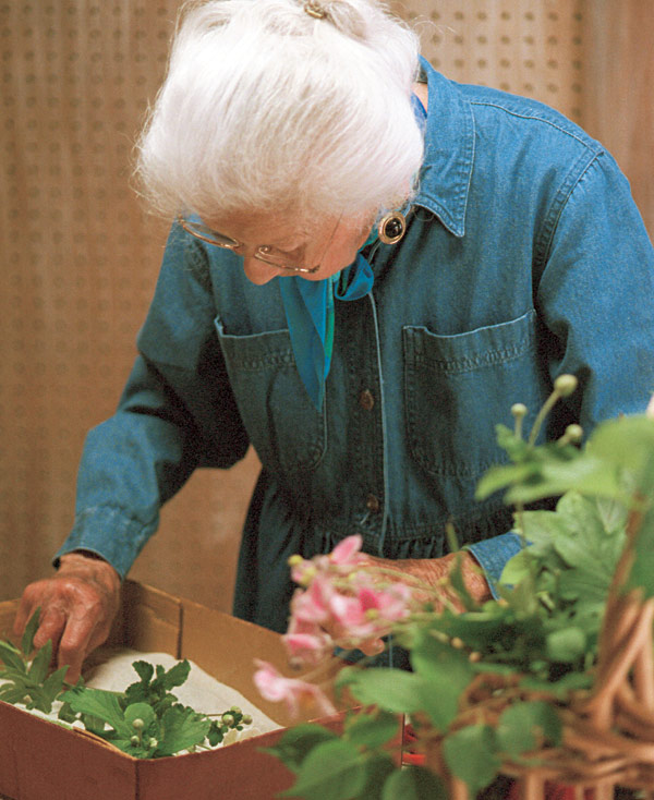 Woman placing flowers in a box with sand