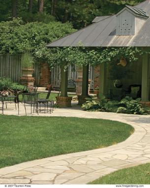 winding sandstone path in front of a house leading to a patio