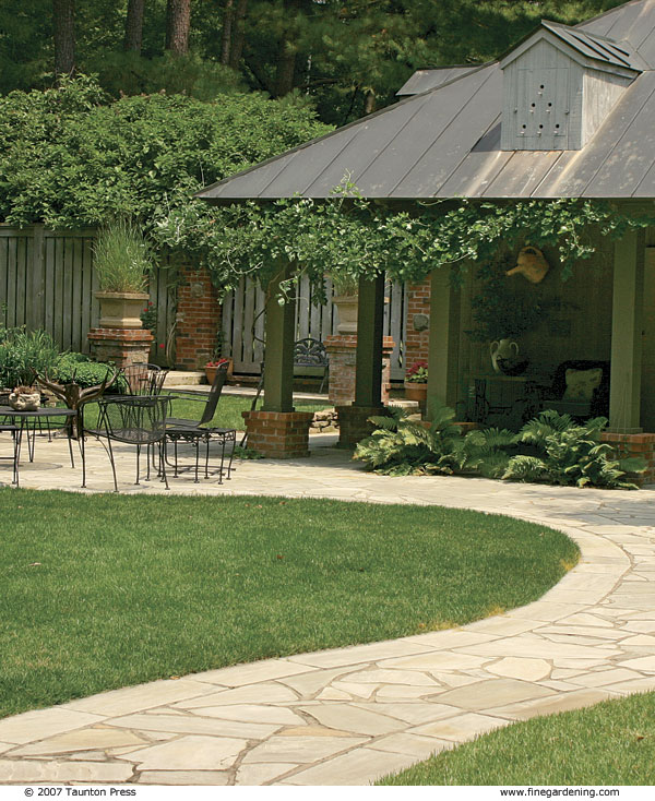 winding sandstone path in front of a house leading to a patio