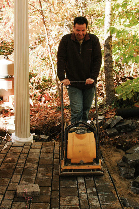 man running the compactor over the patio a final time