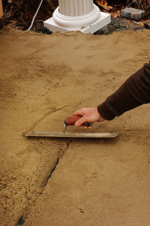 hand smoothing the sand with a trowel