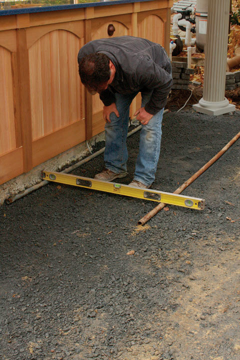 Man bending over to check a level to see if the pipes are level across