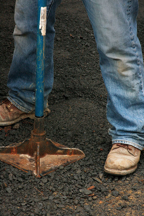 close up of man compacting the first layer with a hand tamper