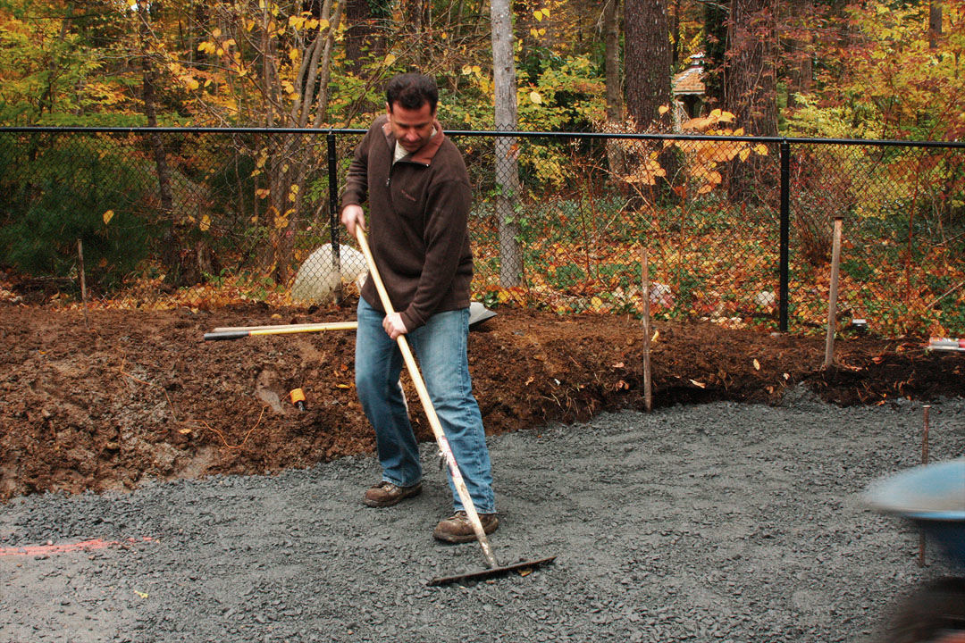 image of man spreading out aggregate evenly with a metal landscape rake