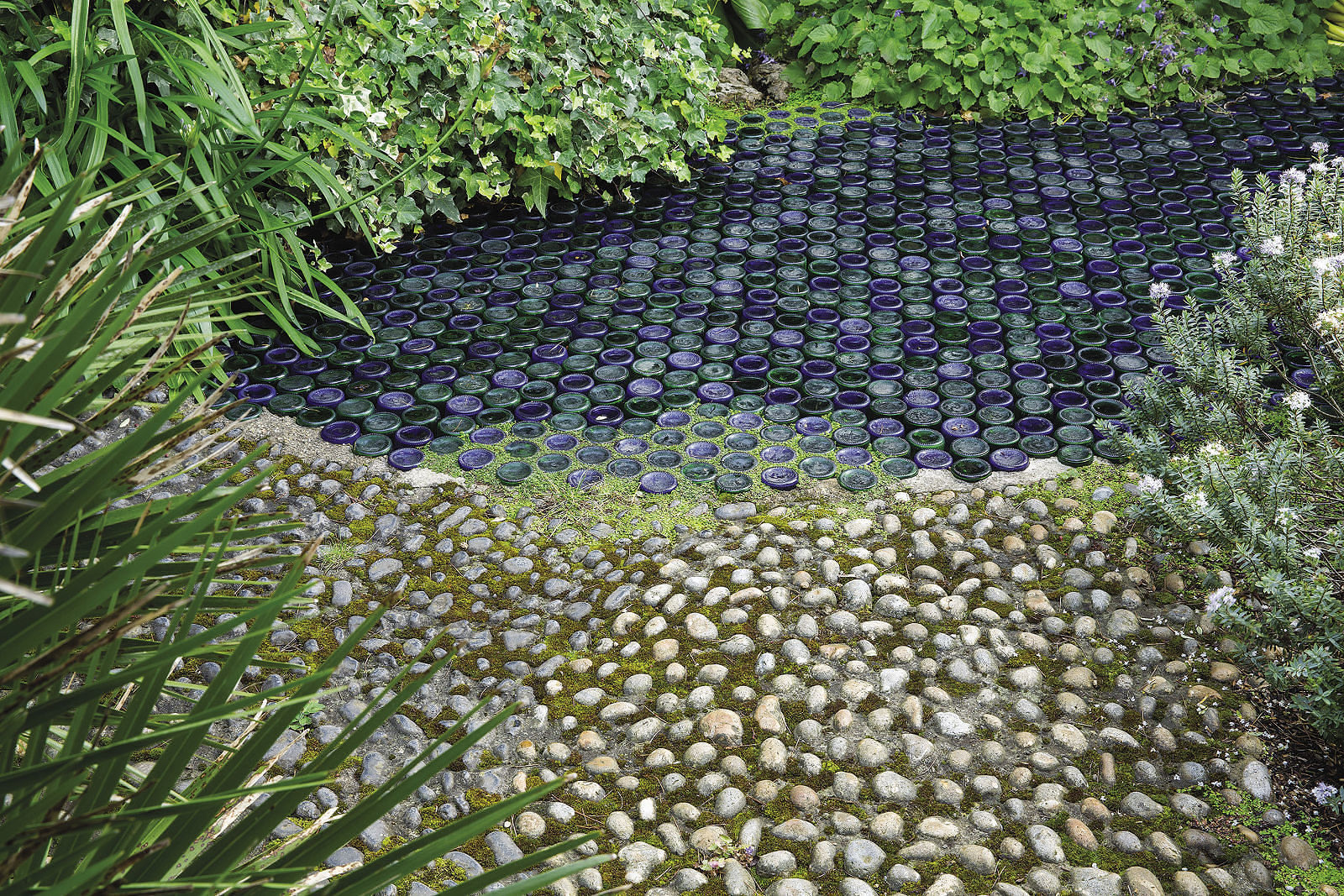 small stones set into mortar and gradually giving way to rows of colored glass bottles