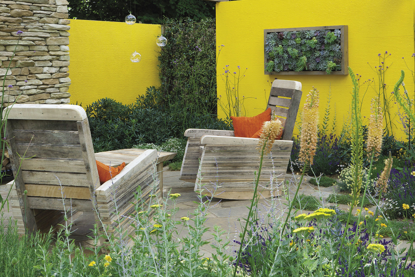 outdoor garden room with cozy rocking chairs, fireplace, yellow walls surrounded by plants