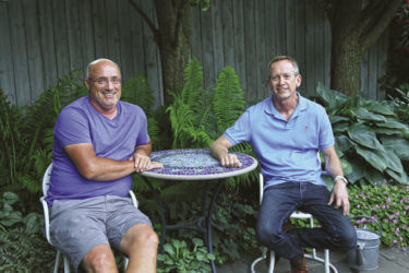 Richard and Tim sitting at a small table on their patio