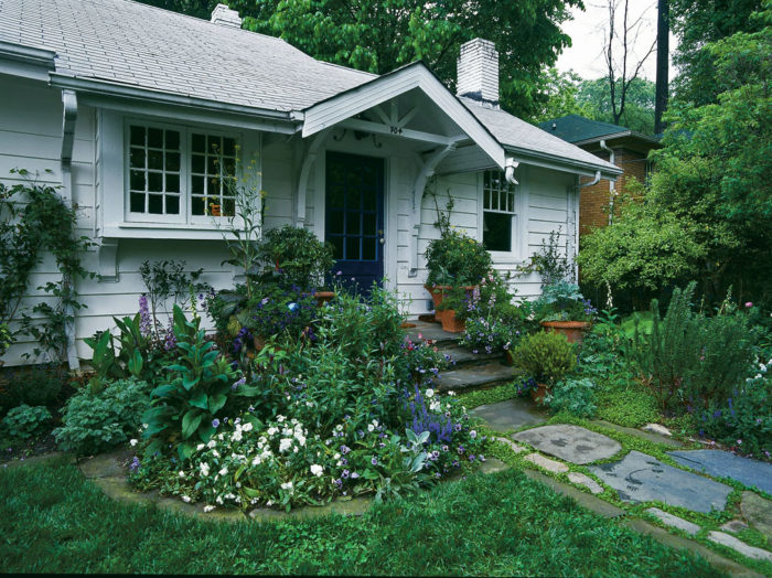 white cottage with cobblestone walkway and islands of plants