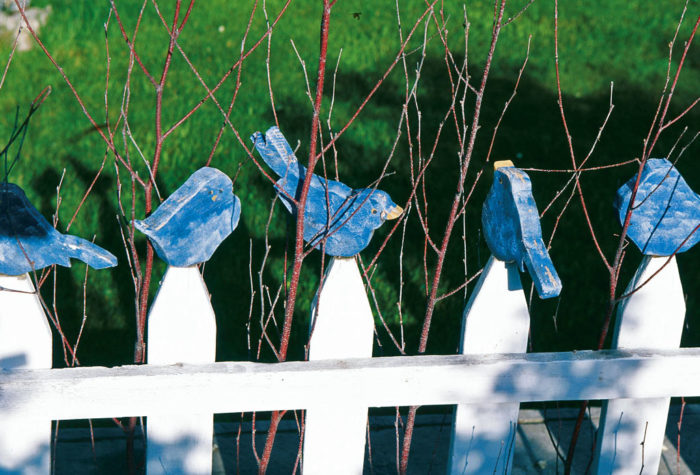 Wooden bluebirds on a white picket fence