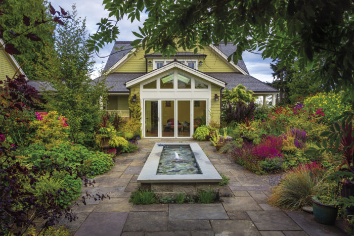 A large rectangular water feature in the center, with nearby ground cover plantings and a protective tree canopy overhead