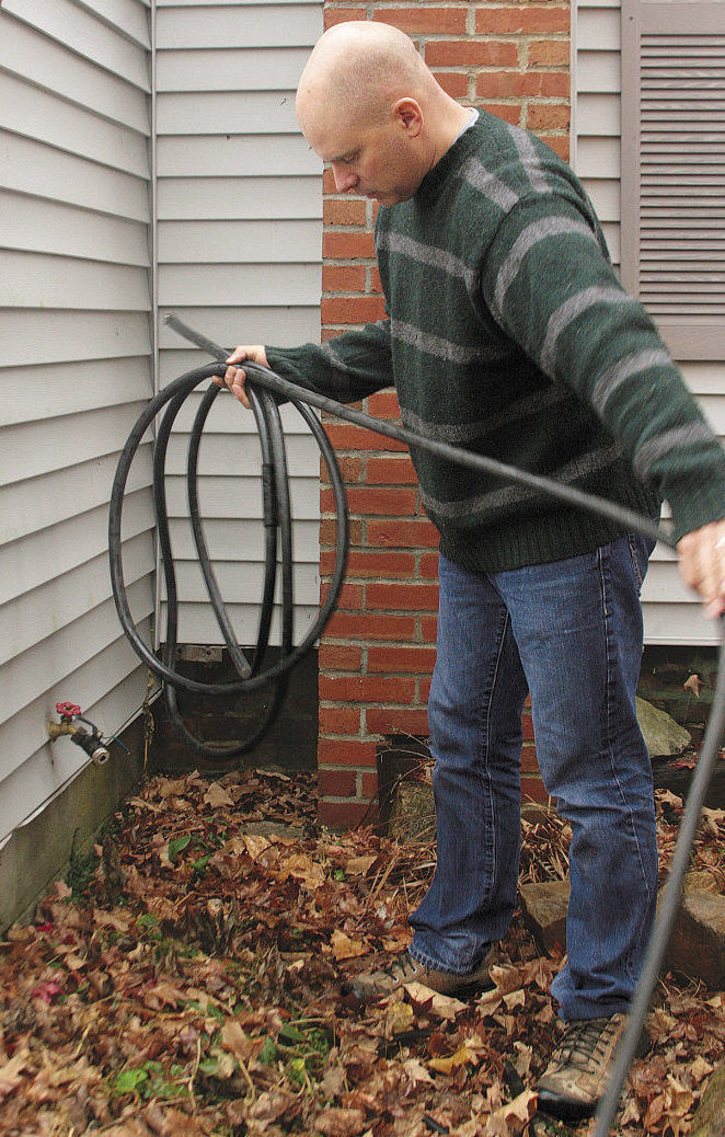 Man winding up a hose for the winter