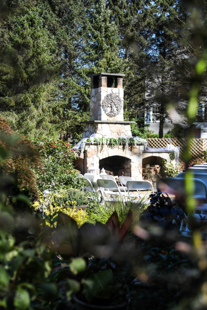 A stone outdoor fireplace set in a garden