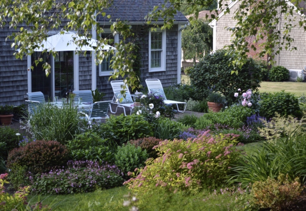 Looking down at a house and patio surrounded by gardens