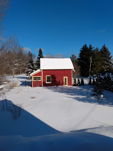 A small red barn surrounded by snow