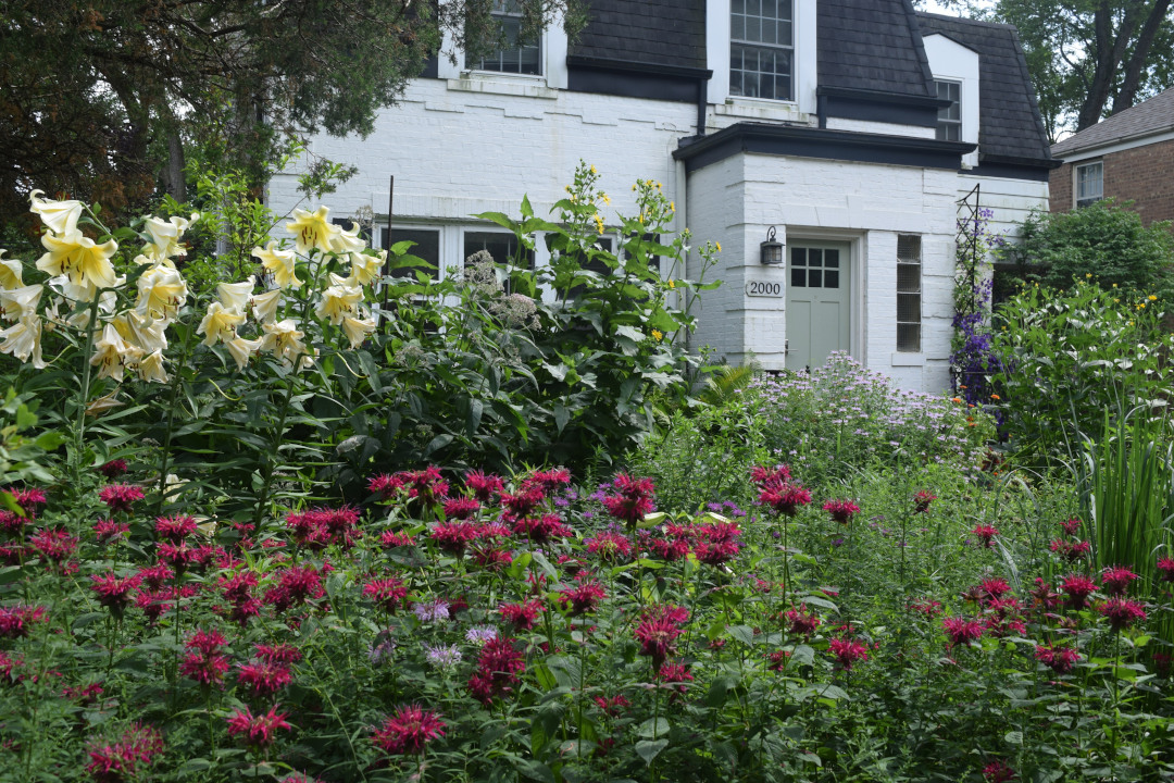 A flower garden in front of a white house