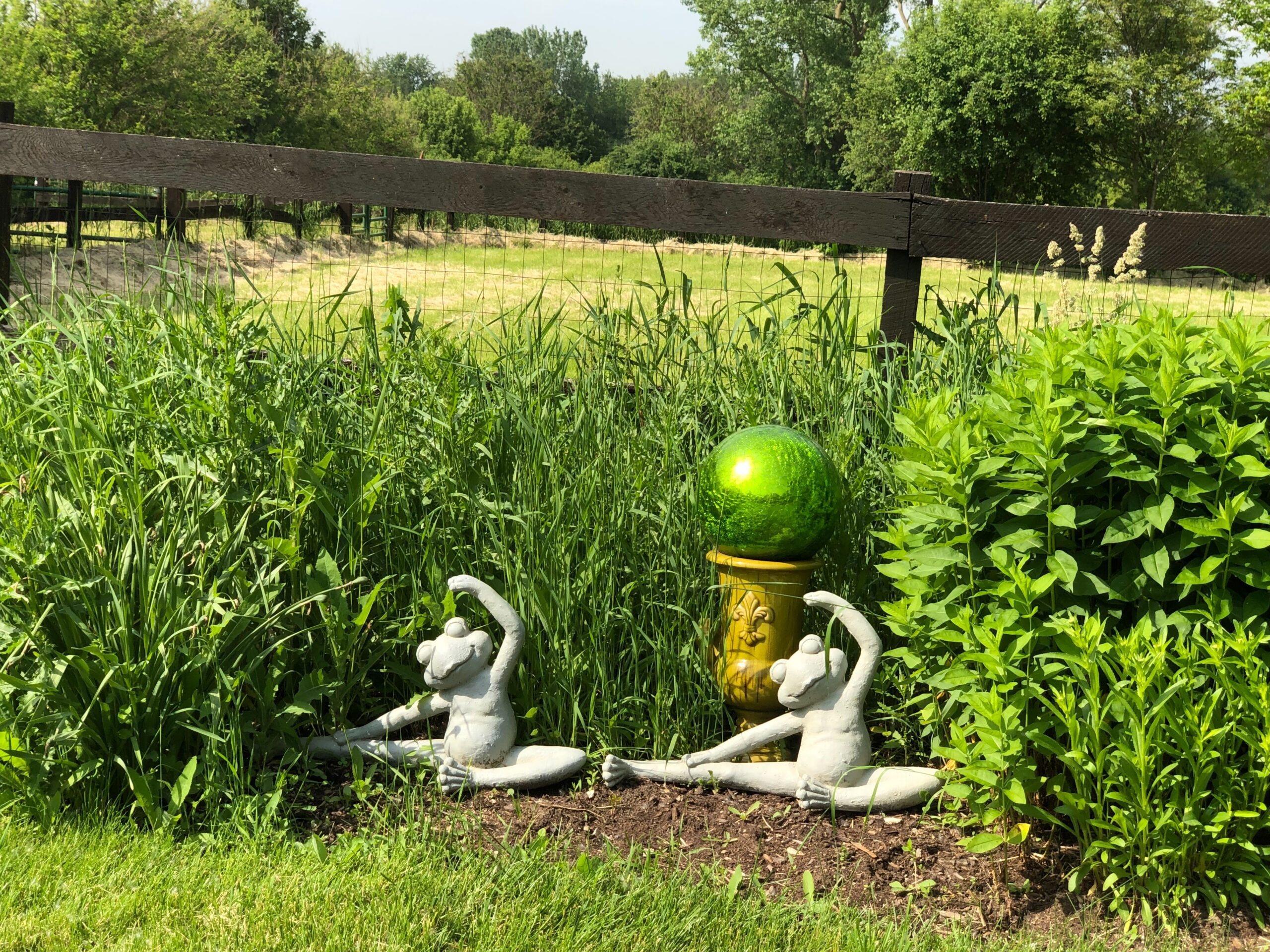 garden art surrounded by perennials not yet blooming