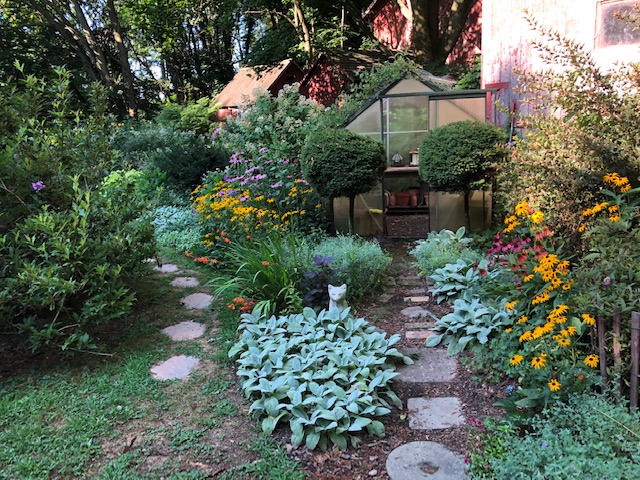 a small greenhouse surrounded by a garden