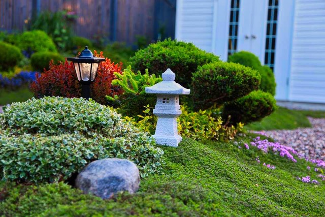 small garden sculpture next to shrubs