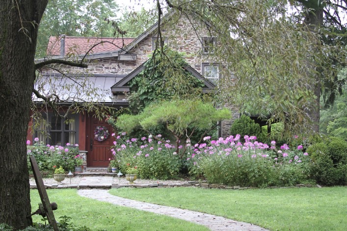 A stone house with pink flowers in front