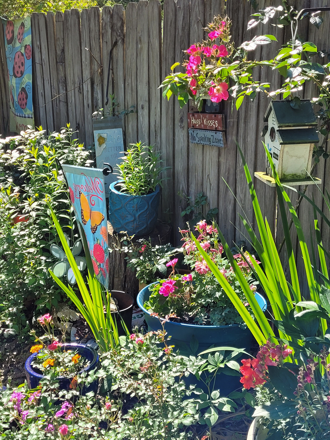 A wooden fence with many flowers in pots in front of it