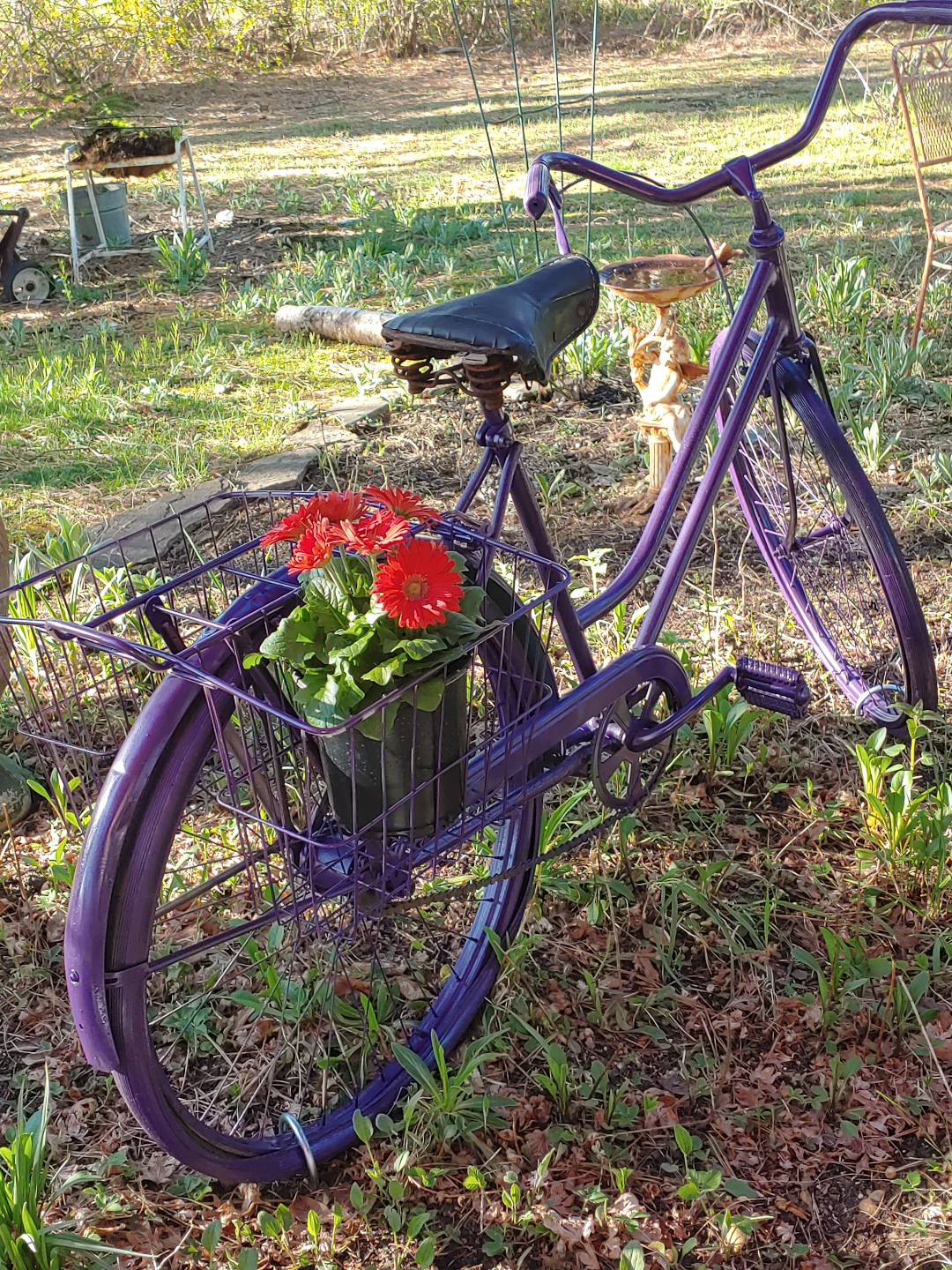 A bicycle painted purple with red daisies in the basket