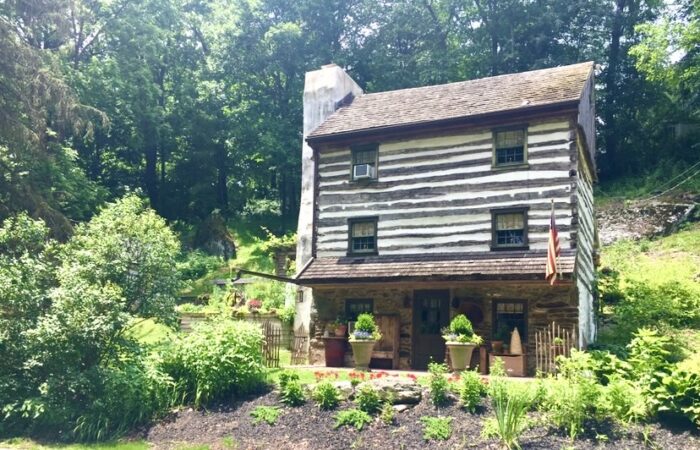 An old log-cabin-style house in a green garden