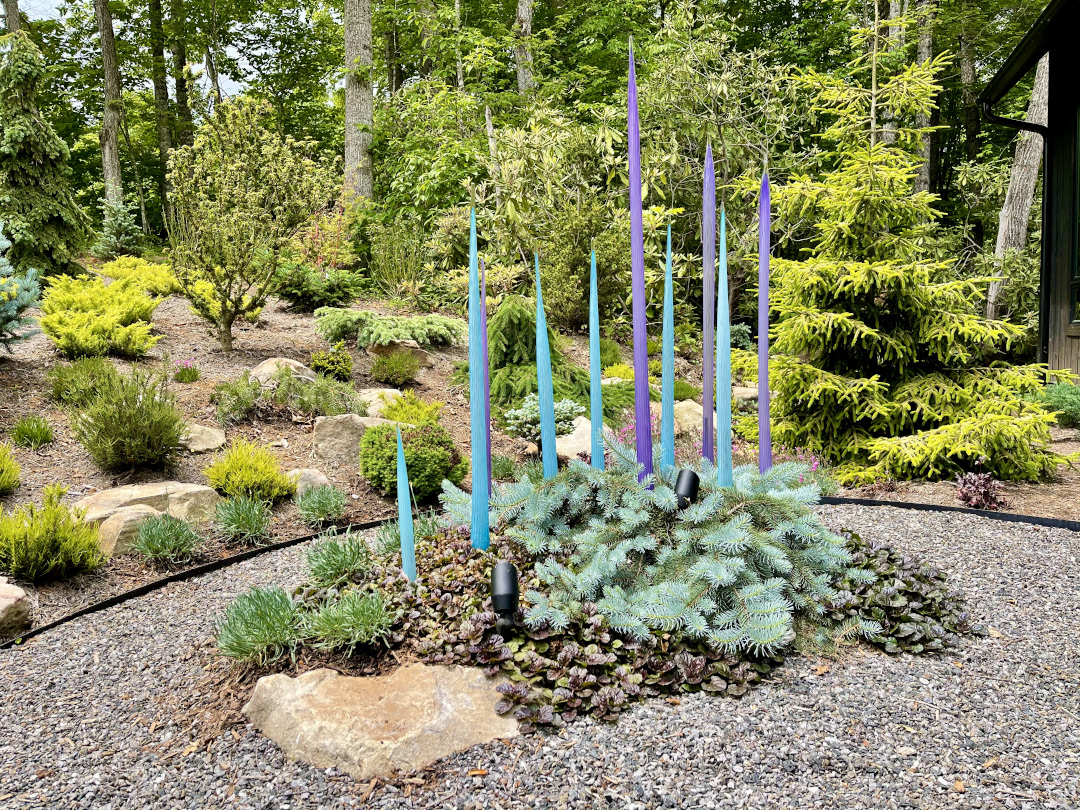 garden bed with lots of conifers and unique garden art