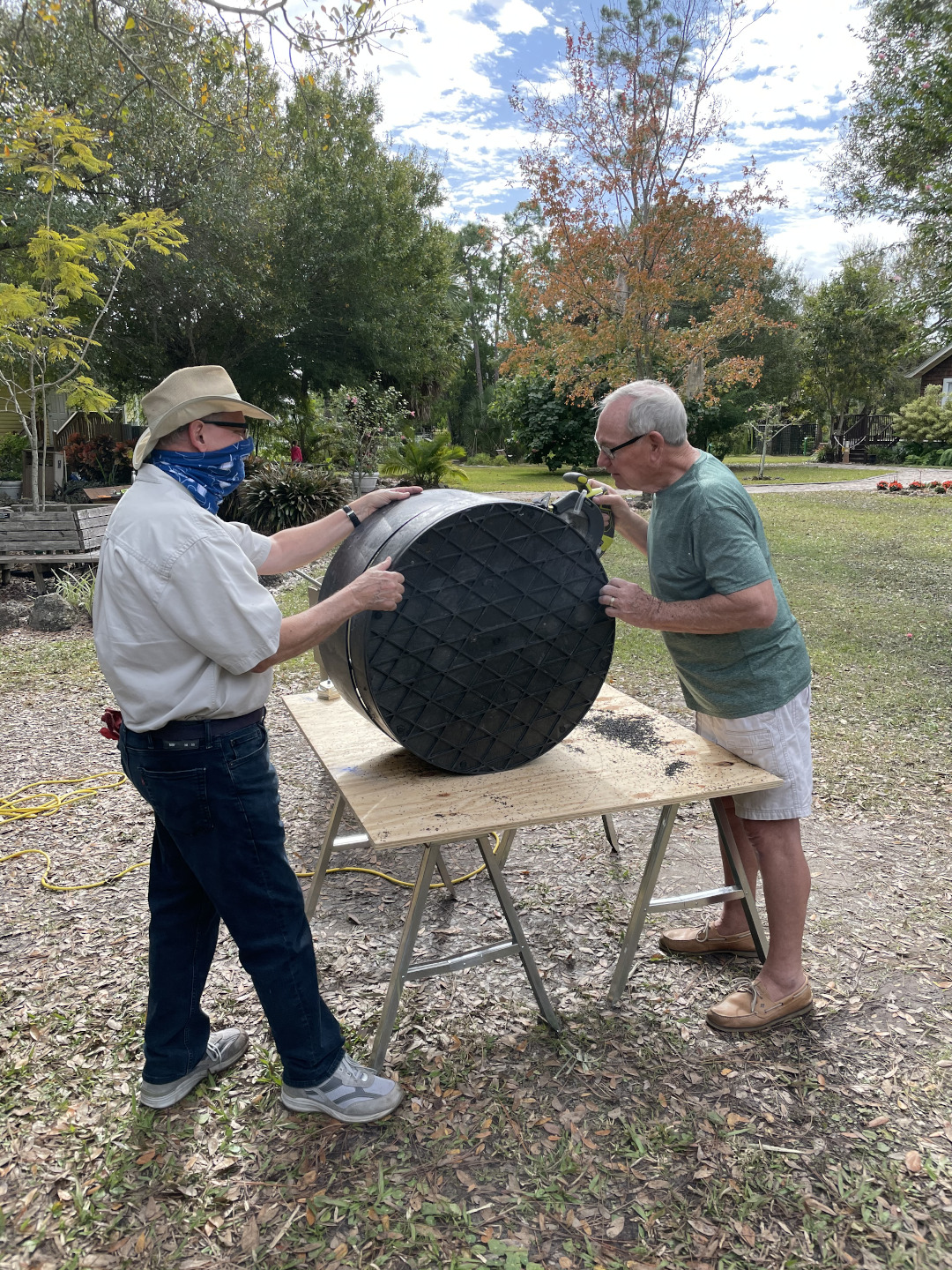 Two men slicing a plastic barrel into rings