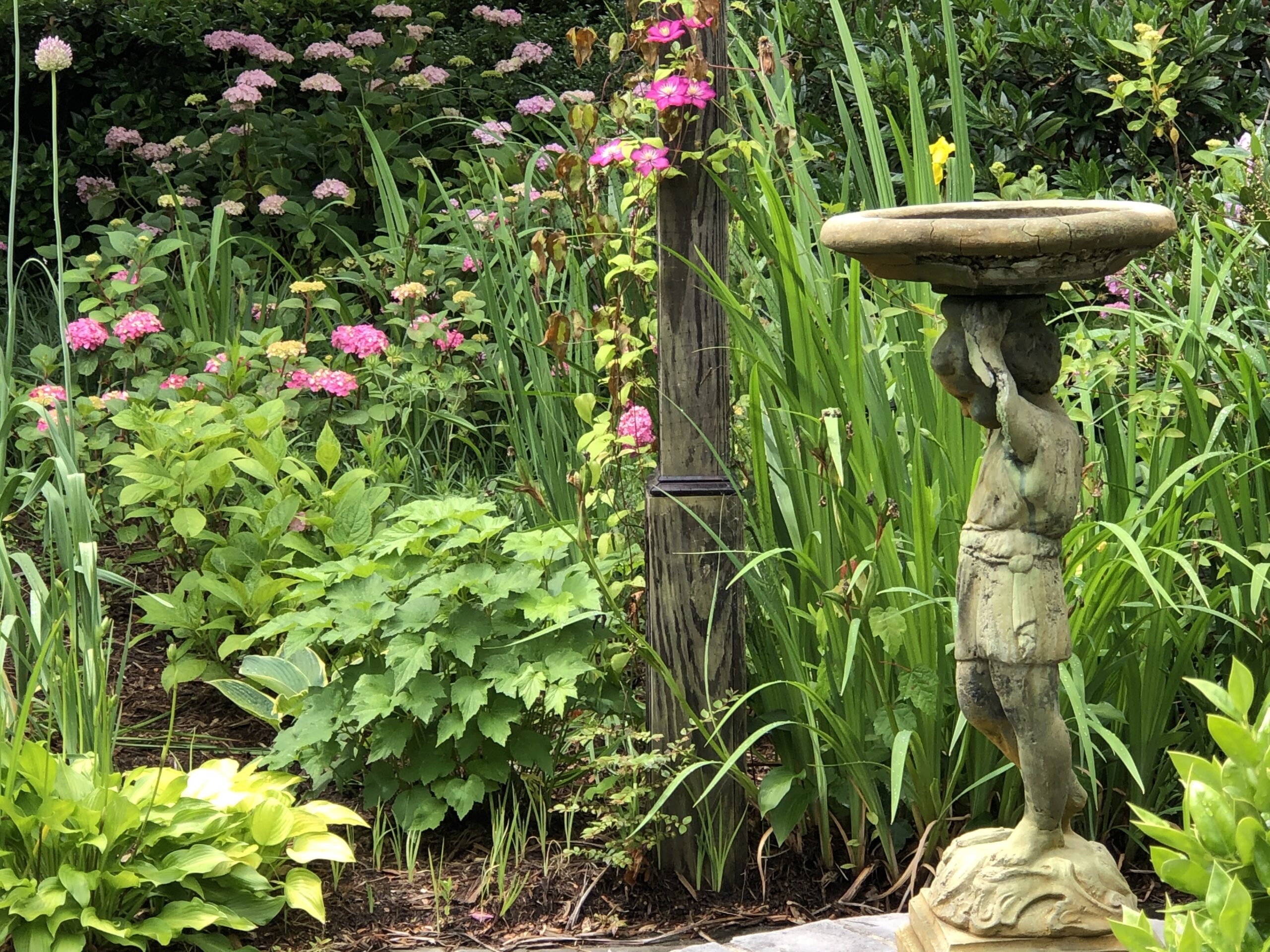 Statue of a child holding a birdbath in a garden