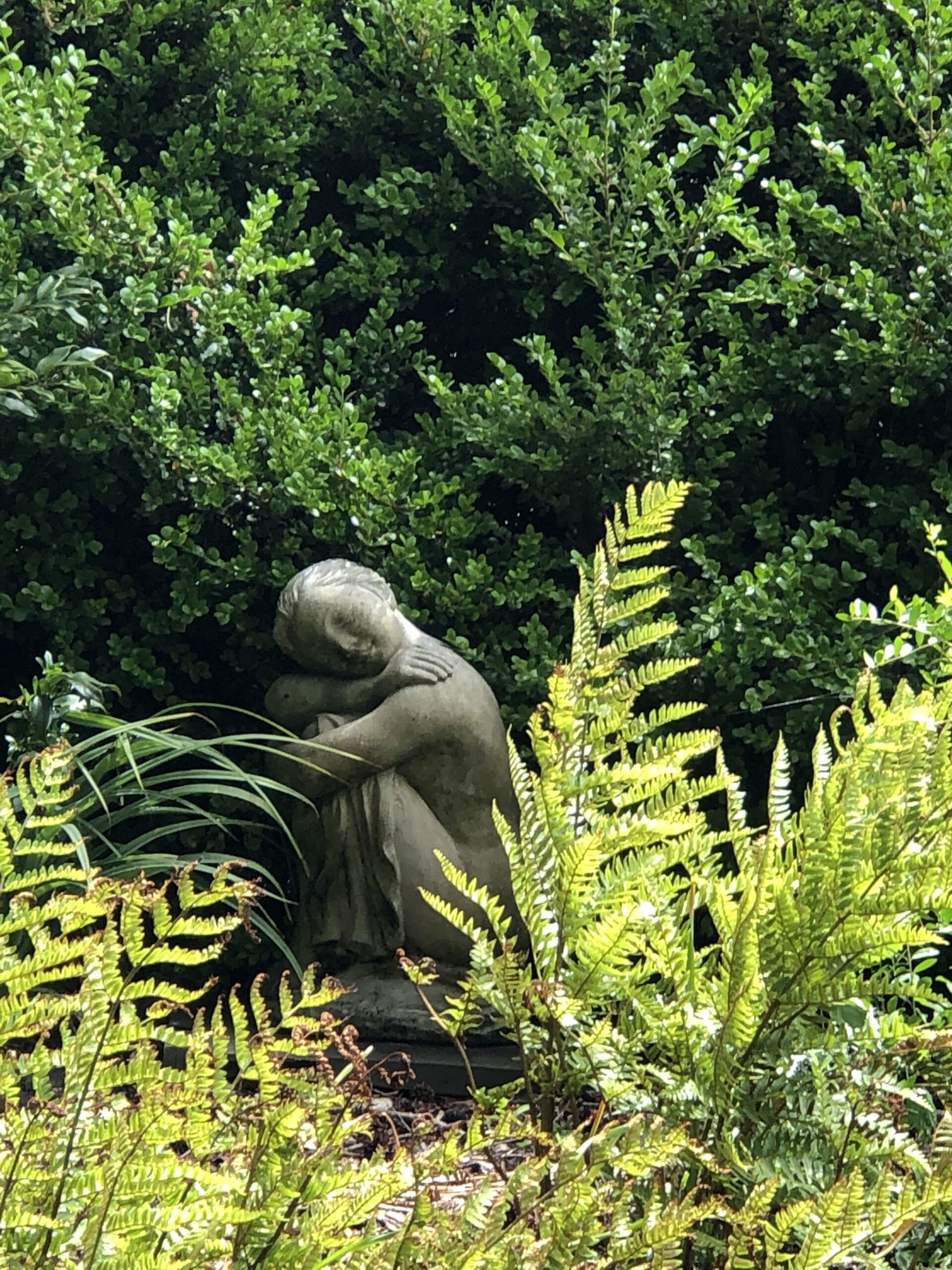 A statue of a sleeping girl surrounded by ferns