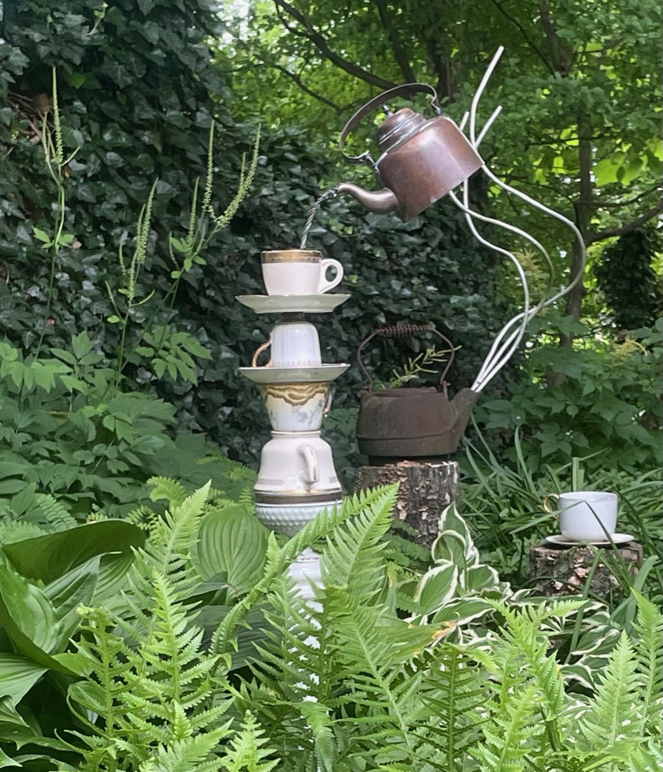 ferns and hostas around a quirky piece of garden art