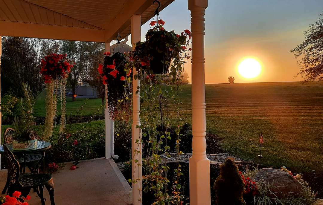 covered porch with hanging baskets overlooking a sunset