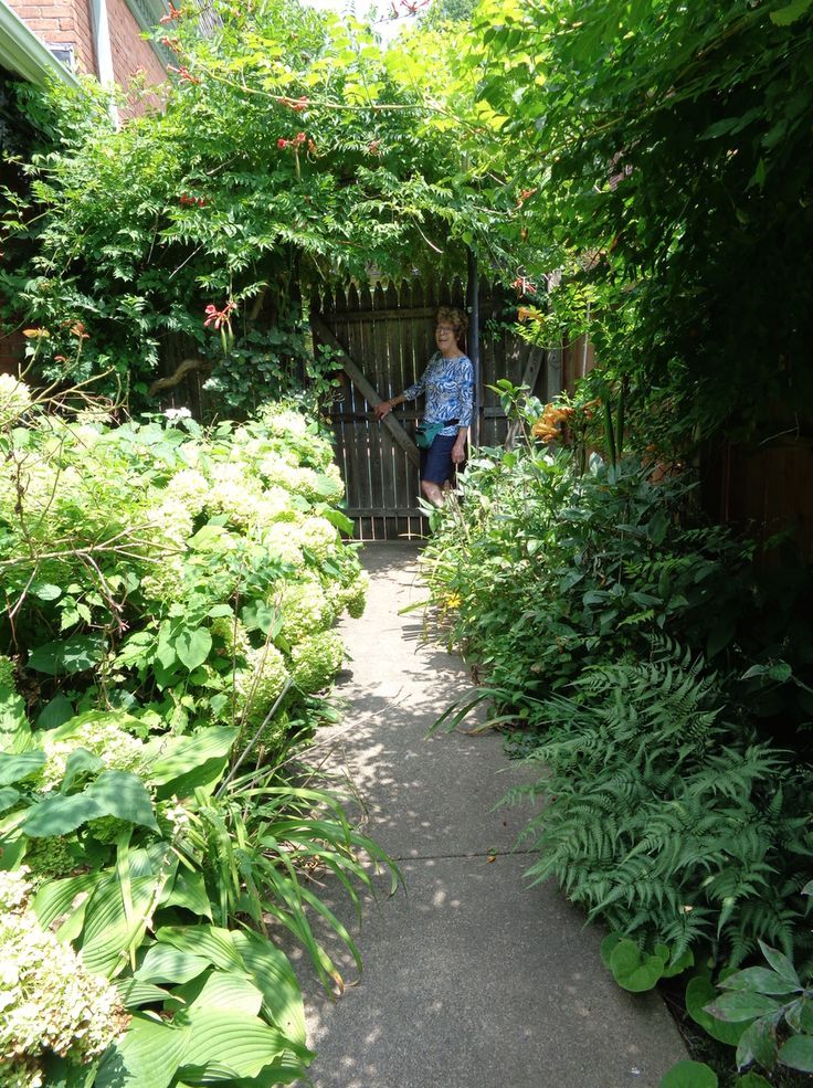 gardener standing at the end of garden path at a gate